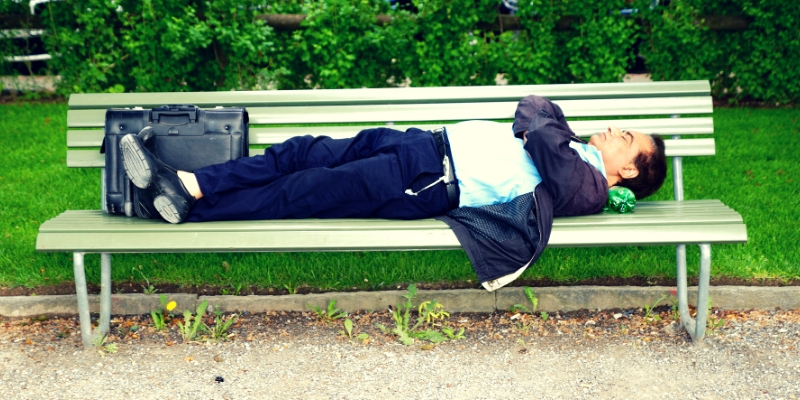 man sleeping on bench outside