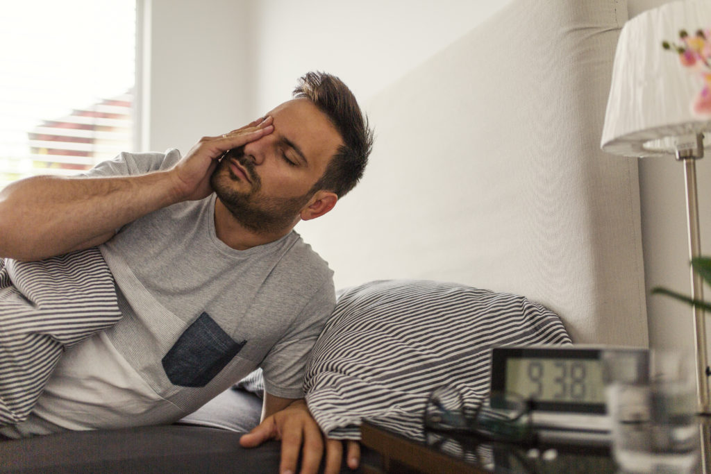 Man in bed struggling to wake up in the morning